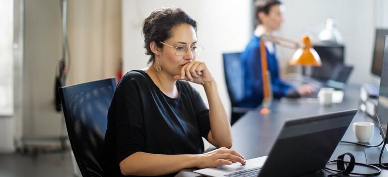 A person sitting at a table using a laptop for online security research